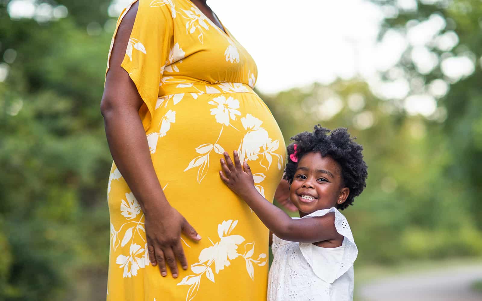 Little girl holding pregnant mom's stomach