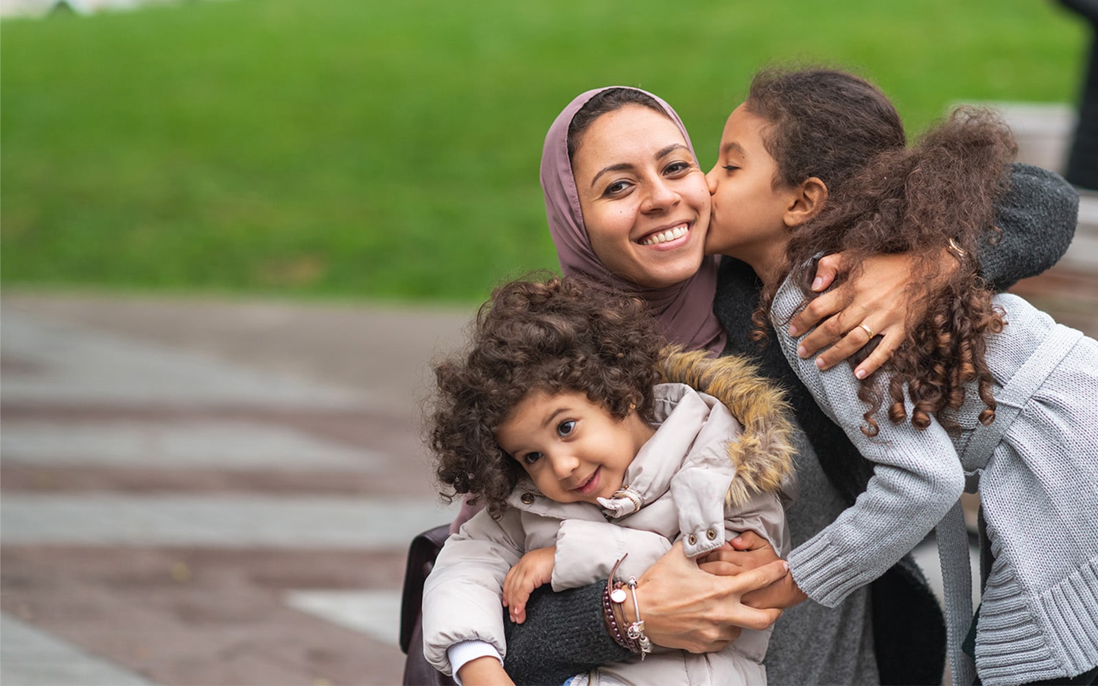 Mother wearing a hijab posing for a photo with her two daughters