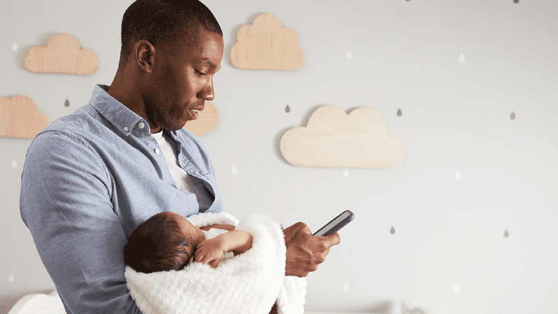 Father holding child and looking up article on phone